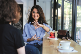 Zwei Frauen sitzen am Tisch mit Getränken.